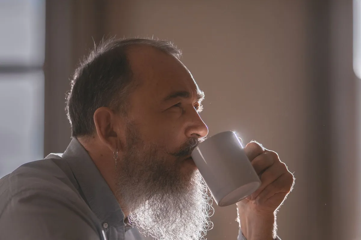 Homme d'une cinquantaine d'années qui boit son café le matin